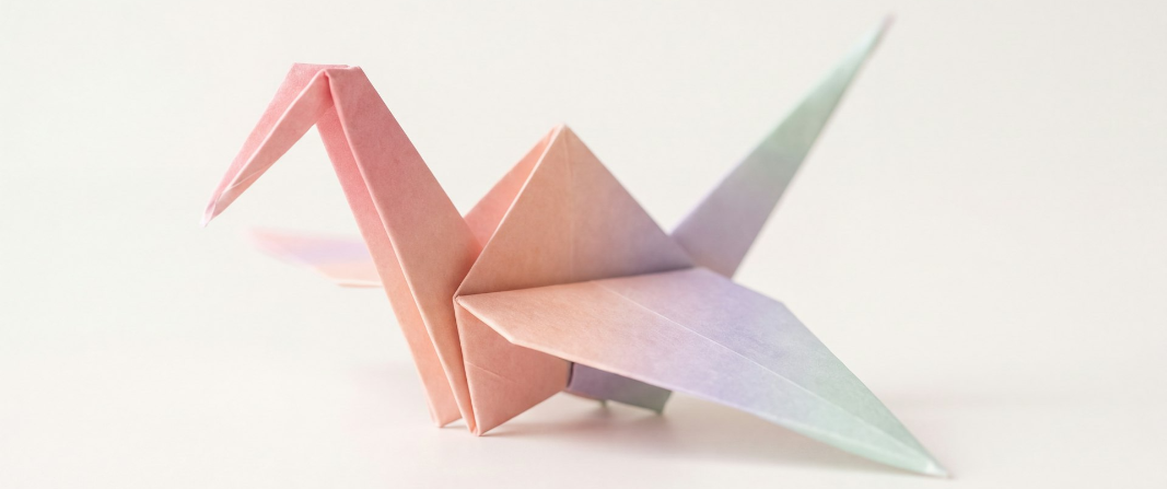 A pastel rainbow origami crane on a white background.